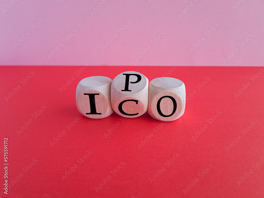 IPO vs ICO. Turned a cube and changed the word 'IPO - initial public offering' to 'ICO - initial coin offering'. Beautiful red table. Pinc background. Business and IPO vs ICO concept. IPO vs ICO. Turned a cube and changed the word 'IPO - initial public offering' to 'ICO - initial coin offering'. Beautiful red table. Pinc background. Business and IPO vs ICO concept.