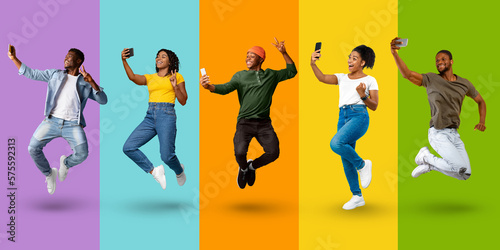 Smiling emotional young black people in casual jumping, make selfie and enjoy win