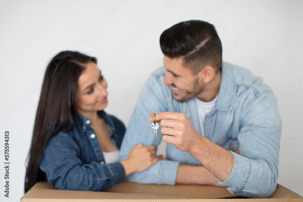 Relocation Concept. Happy Young Spouses Leaning On Cardboard Box And Holding Keys Relocation Concept. Happy Young Spouses Leaning On Cardboard Box And Holding Keys