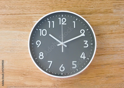 Top view of a round black and white clock isolated on wooden background. time concept. minimalistic.