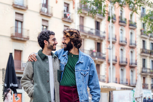couple of gay men walk smiling embraced, concept of freedom and love between people of the same sex © Raul Mellado