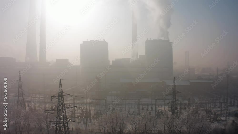 Takeoff over the pipes of a thermal power plant with harmful emissions into the air polluting the atmosphere and the environment against the backdrop of houses in the city of Bishkek in thick smog