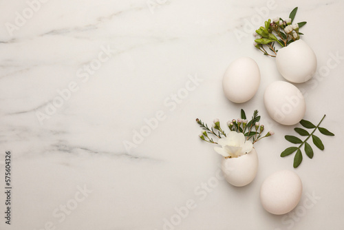 Canvas Print Easter eggs and beautiful flowers on white marble table, flat lay