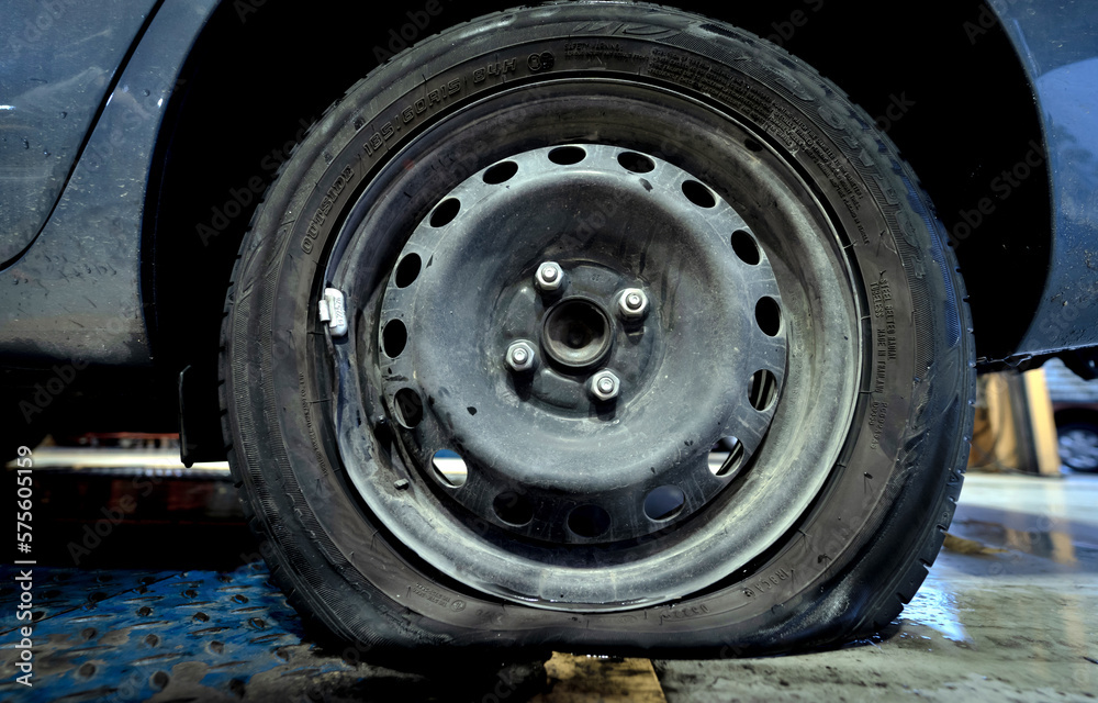 Car with a punctured and broken wheel in a car repair shop Car with a punctured and broken wheel in a car repair shop