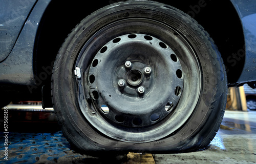 Car with a punctured and broken wheel in a car repair shop