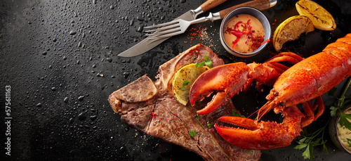 Tasty lobster and beef steak on wet surface