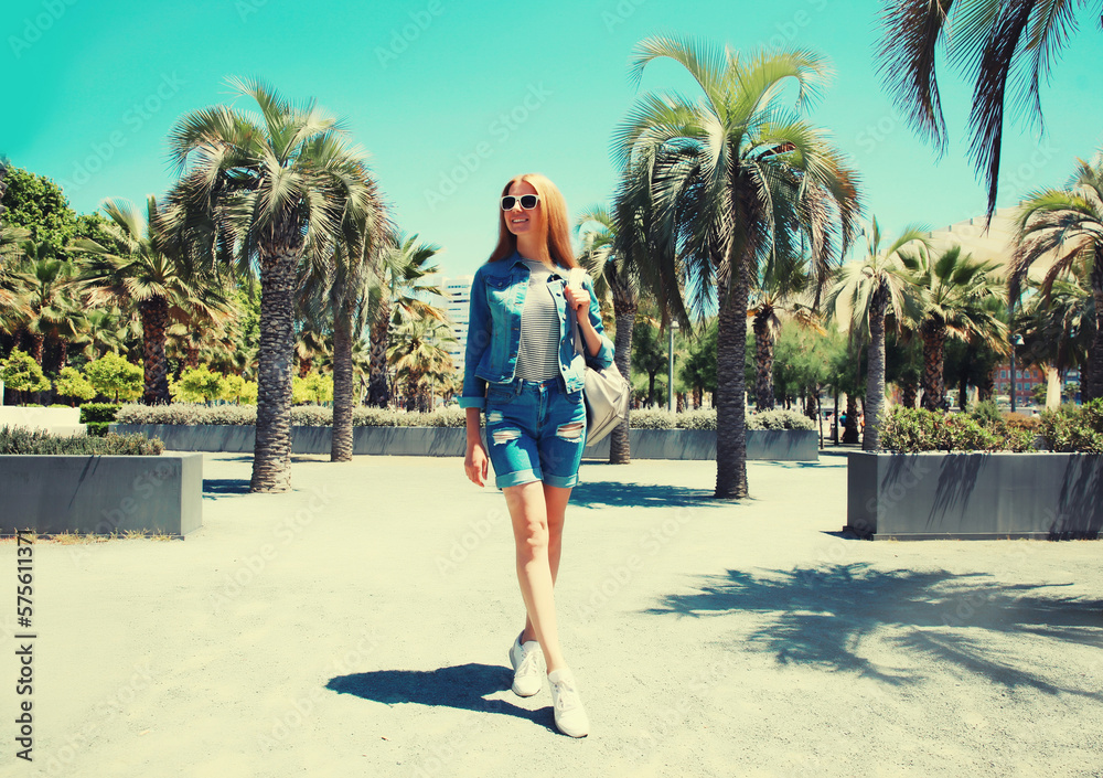 Portrait of beautiful young woman in summer park wearing backpack on palm tree background