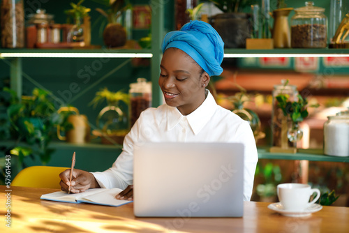 Black woman entrepreneur using laptop while sitting at cafe