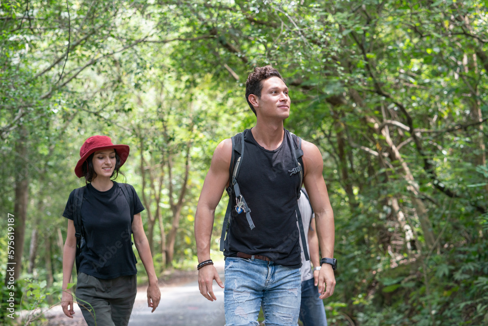 Group of happy friends with backpacks hiking together in forest. Diversity of young traveling adventure trekking with nature in holiday summer Group of happy friends with backpacks hiking together in forest. Diversity of young traveling adventure trekking with nature in holiday summer