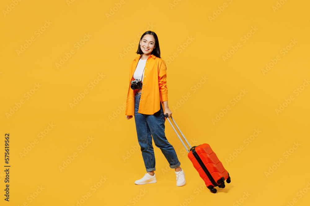Sideways young woman wear summer casual clothes walk go with suitcase bag isolated on plain yellow background. Tourist travel abroad in free spare time rest getaway. Air flight trip journey concept. Sideways young woman wear summer casual clothes walk go with suitcase bag isolated on plain yellow background. Tourist travel abroad in free spare time rest getaway. Air flight trip journey concept.