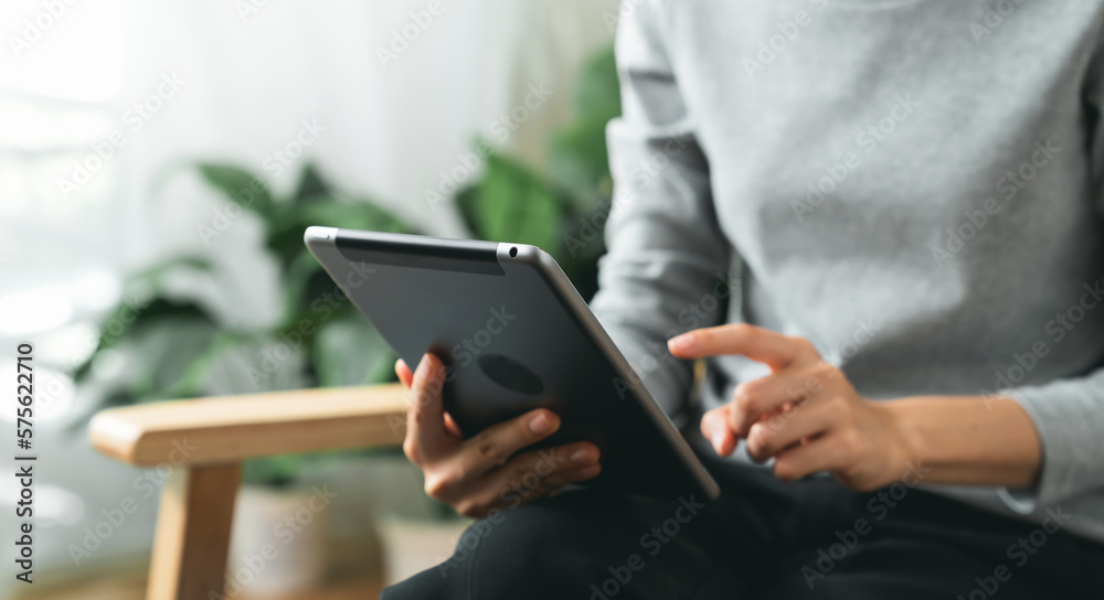 Hands holding digital tablet with using social media on sofa in living room. Hands holding digital tablet with using social media on sofa in living room.