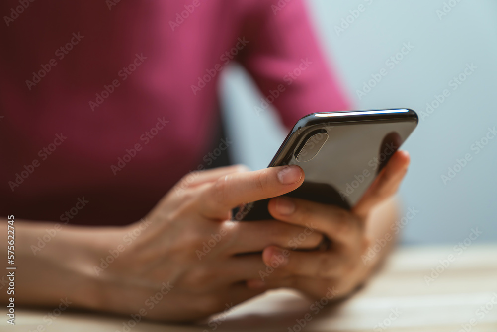 Hand holding smartphone with using social media on internet on table.