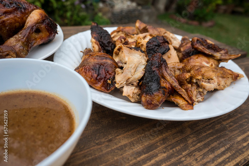 A plate of chopped Lechon Manok, or roasted chicken served outside at a bench with gravy. photo