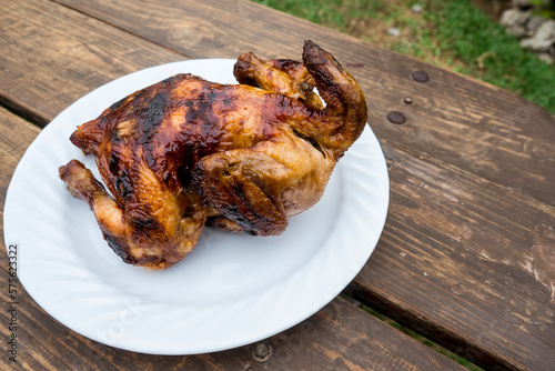 A plate of Lechon Manok, or roasted chicken served outside at a bench. photo