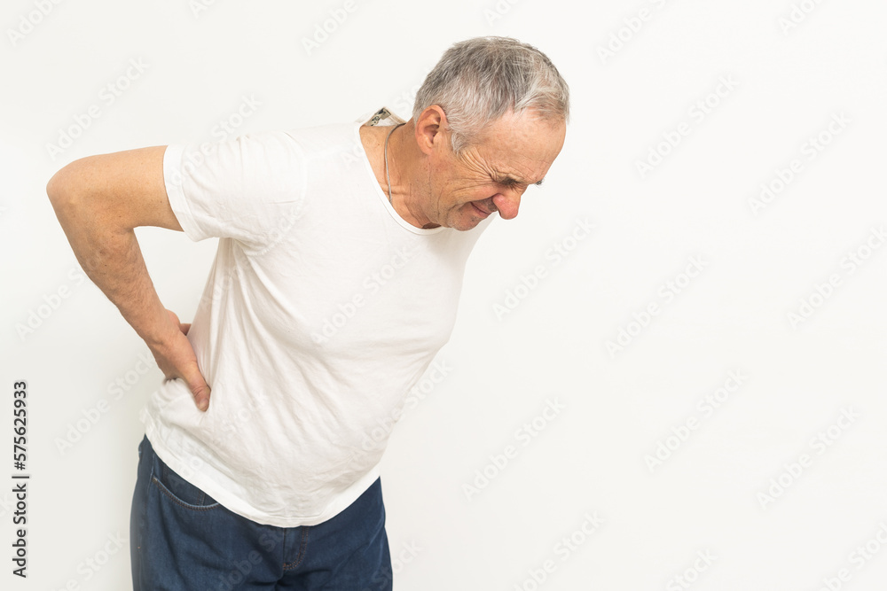 Caucasian old senior elderly unhealthy sickness grey male grandpa near sofa at home alone holding hands on back having emergency painful muscle and backache injury problem. Caucasian old senior elderly unhealthy sickness grey male grandpa near sofa at home alone holding hands on back having emergency painful muscle and backache injury problem.