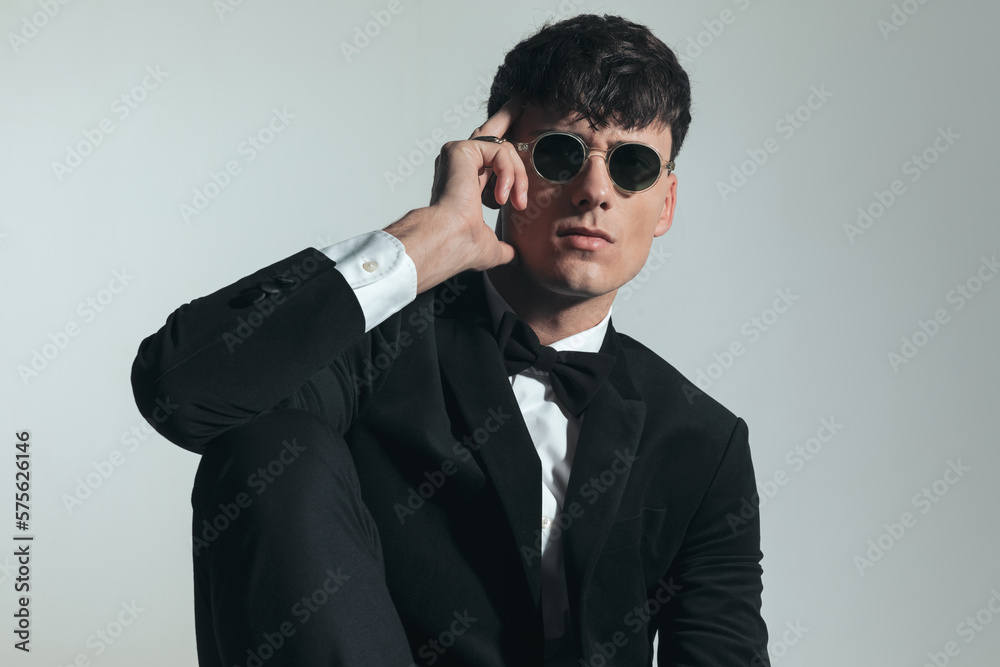 sexy fashion man in black tuxedo touching temple with fingers sexy fashion man in black tuxedo touching temple with fingers
