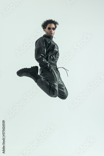 casual man jumping and kicking with hands in pockets