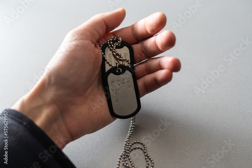 blank army dog tags in hand on white background