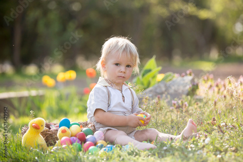Sweet toddler boy with bunny ears, egg hunting for Easter, child and Easter day traditions