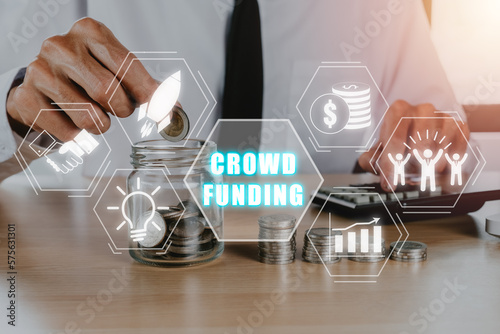 Crowdfunding concept, Business person hand putting money into jar glass with crowdfunding icon on virtual screen, Collaborative, Growth and return. photo