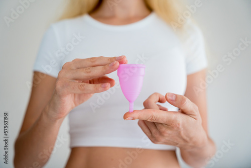 Young beautiful woman at home holding a menstrual cup in her hands