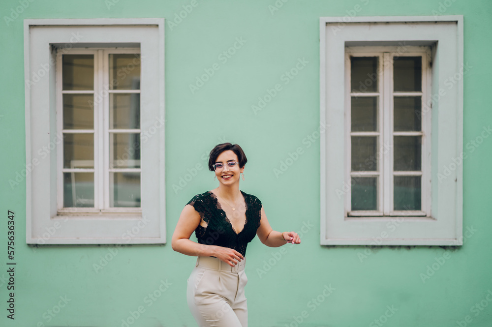Woman wearing beige pants and a black lace top walking in the city street Woman wearing beige pants and a black lace top walking in the city street