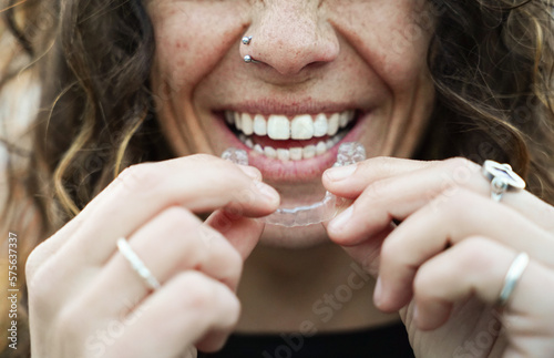 smiling woman putting on an invisible tooth apparatus. aesthetic orthodontics