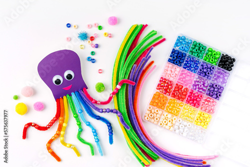 Funny octopus made of beads and pipe cleaners with different colorful and materials for DIY art activity for kids. Cute children's crafts, creativity and hobby. Development of fine motor skills photo