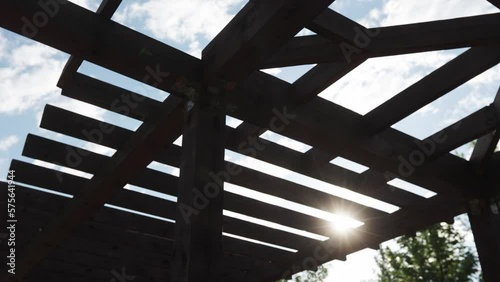 Wooden pergola in a city recreation park with a lake in the residential area