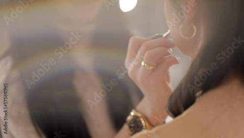 The stylist applies lipstick to the lips of the female model. Woman making make up applying lipstick on a lip. Professional makeup. Tutorial makeup master class