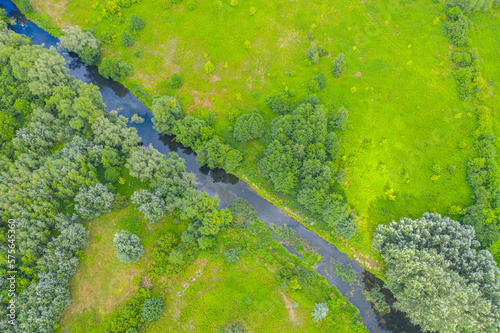 Top down view on exotic winding river flows through green wetlands. Birds eye view of zig-zag creek. Ukraine, Europe. Cinematic aerial shot. Discover the beauty of earth. Filmed in 4k, drone video.