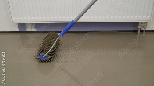 Pouring with self-levelling compound for fine leveling. The process of laying a self-leveling floor. Air pumping out of the bulk floor. Bulk floor close-up. Roll out the floor with a notched trowel.