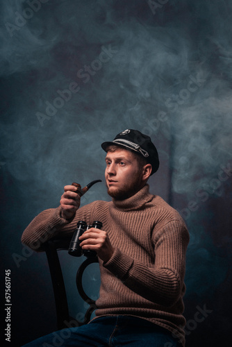 Vessel captain. A man in a sweater and cap. Smokes a pipe. Male profession.