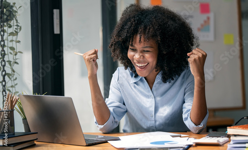 Successful and exciting african american businesswoman excited to winning on her laptop computer at work.