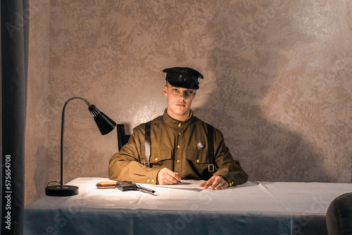 Soldier of the Russian army of the 20th century. Civil service officer in a cap, military uniform and with a pistol. A young man with strong will.