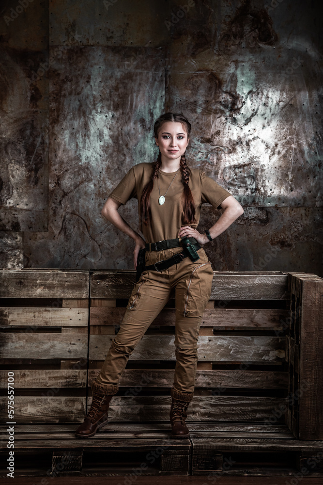 American pilot. A beautiful young woman in a uniform and with a weapon on the background of a metal wall. Staged photo. Studio light. American pilot. A beautiful young woman in a uniform and with a weapon on the background of a metal wall. Staged photo. Studio light.