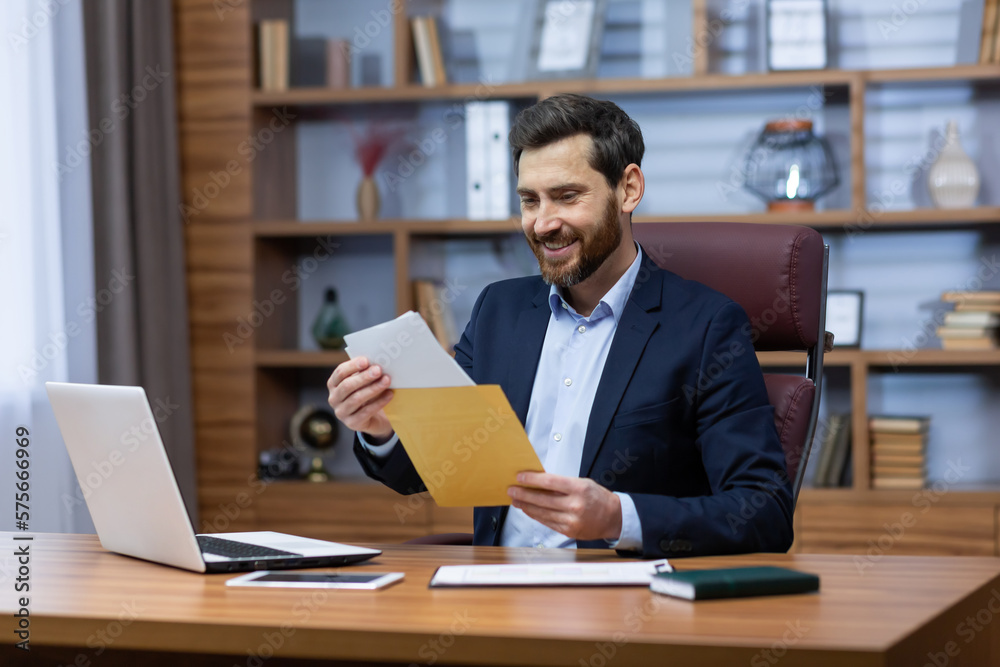 Successful mature man inside office at work, senior man with beard in home office received mail fox, bank notification, businessman reading good news in envelope, satisfied with achievement results.
