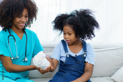African - American black little girl have an accident at her right arm and see the doctor in hospital. Orthopedic doctor checking the splint arm of girl patient.