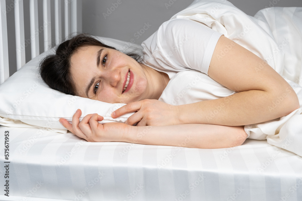 A woman lies in bed on her side on a pillow made of hollowfiber, hollow fiber A woman lies in bed on her side on a pillow made of hollowfiber, hollow fiber