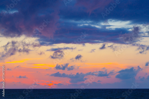 purple clouds in the setting sun with rich color palette and a dark blue sea