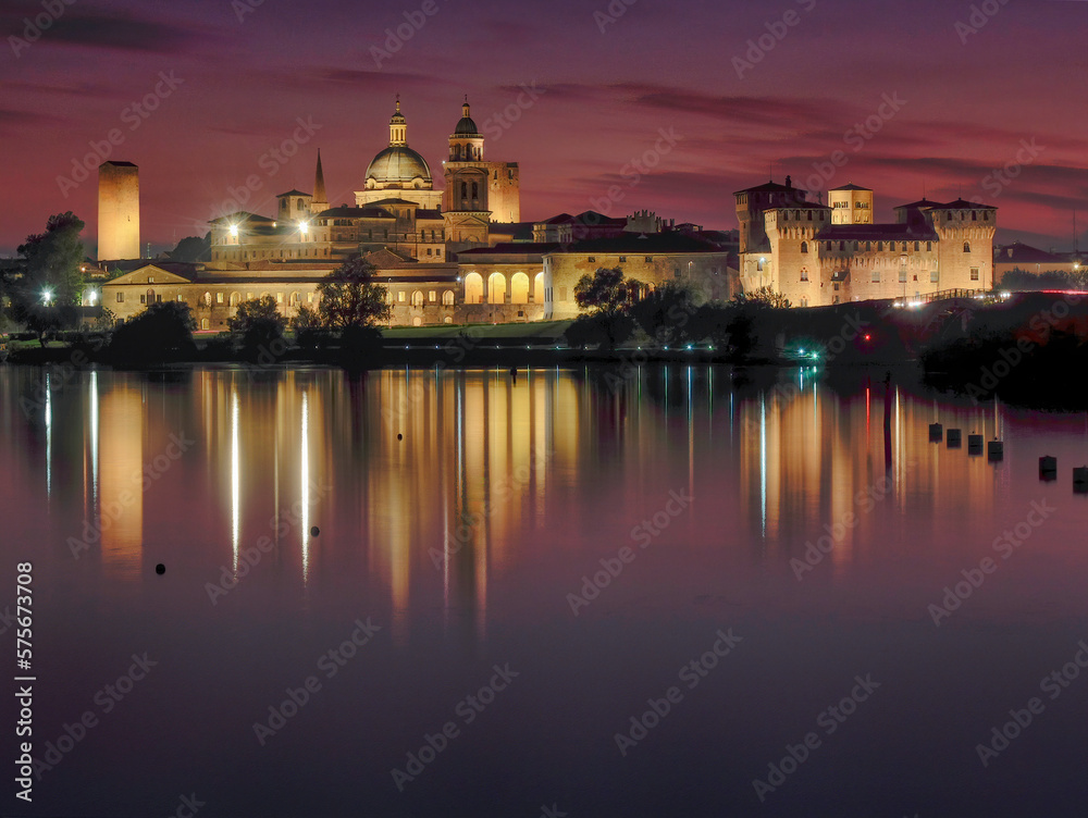 Skyline of the Renaissance city of Mantua at dusk with reflections in the water of the lake formed by the Mincio River.