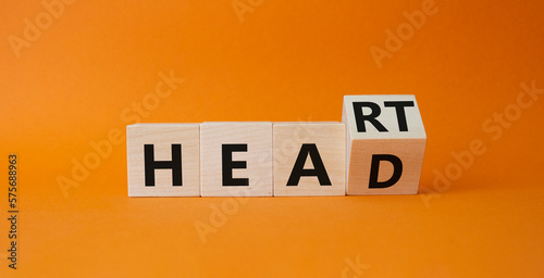 Heart and Head symbol. Turnedn wooden cube with words Head and Heart. Beautiful orange background. Business and Heart and Head concept. Copy space photo