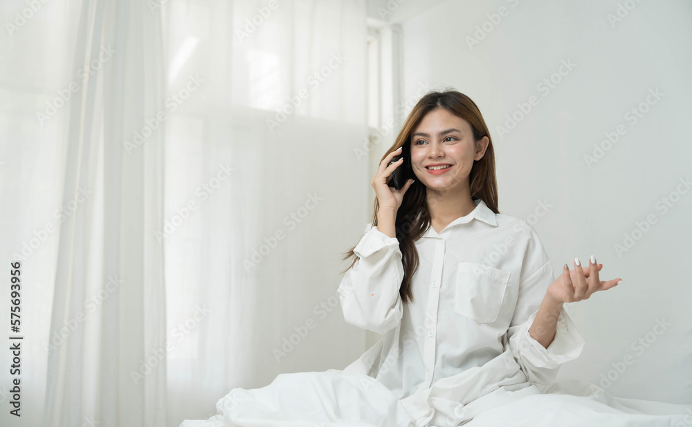 Beautiful young asian woman smiling sitting relax on the bed in the morning, girl using mobile smart phone talking enjoy, communication and social network concept. Beautiful young asian woman smiling sitting relax on the bed in the morning, girl using mobile smart phone talking enjoy, communication and social network concept.