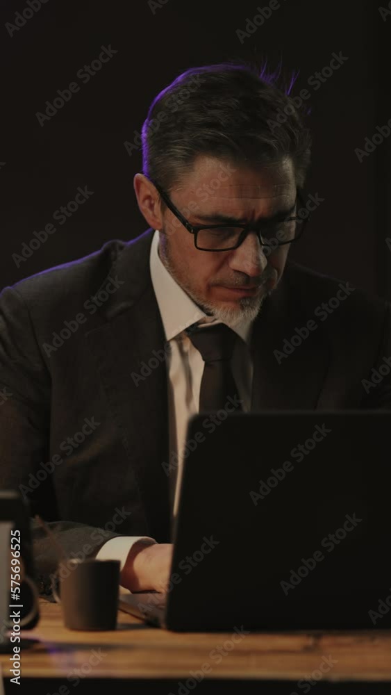 Businessman sitting at desk with laptop computer in jacket and tie. Entrepreneur working late in office. Older, middle aged, mid adult, man in his 40s or 50s in business casual.