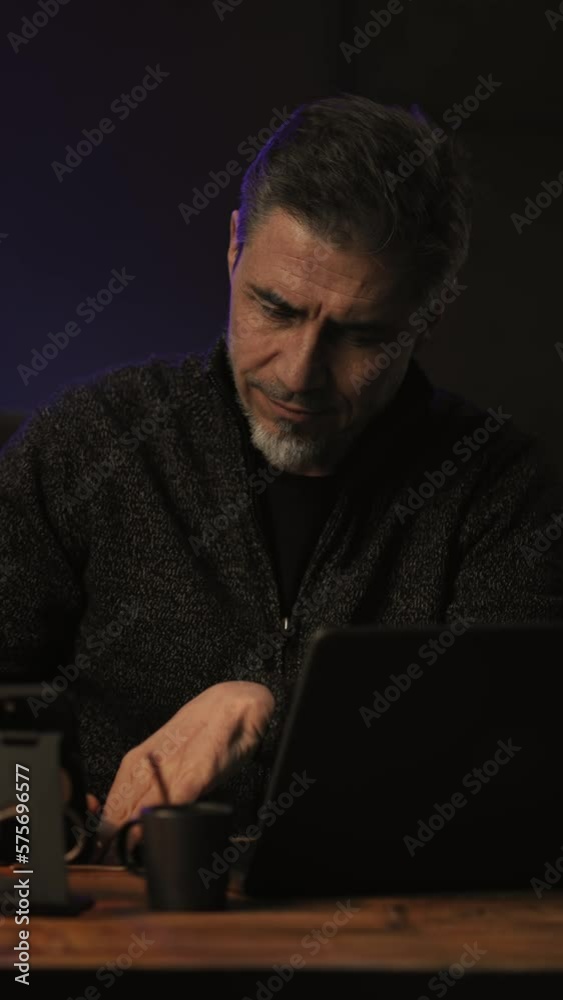 Business portrait - Businessman sitting at desk with laptop computer. Entrepreneur working late in office, smiling. Happy, middle aged, mid adult, man in his 40s or 50s in casual sweater .