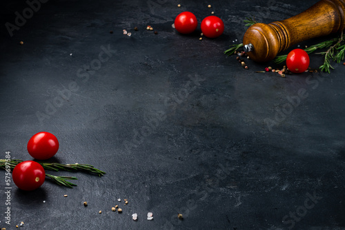 Dark food background with tomatoes, herbs and spices, copy space.