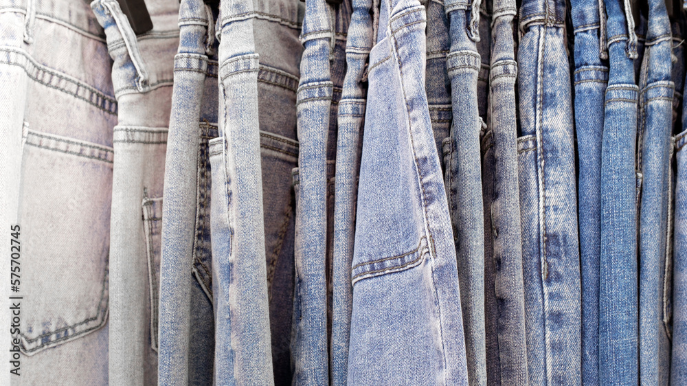 Many jeans hanging on arack. Row of pants denim jeans hanging in closet, concept of buy , sell , shopping and jeans fashion