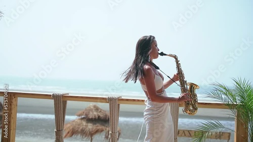 An attractive girl is in a cafe and blows sounds on a golden saxophone
