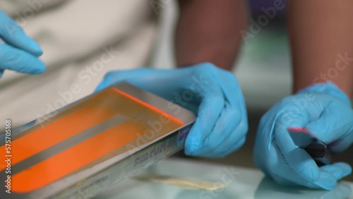 Someone showing orange paint spread on a metal bar