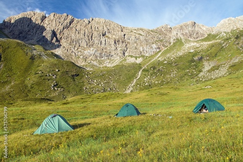 three tents on a meadow in the mountains